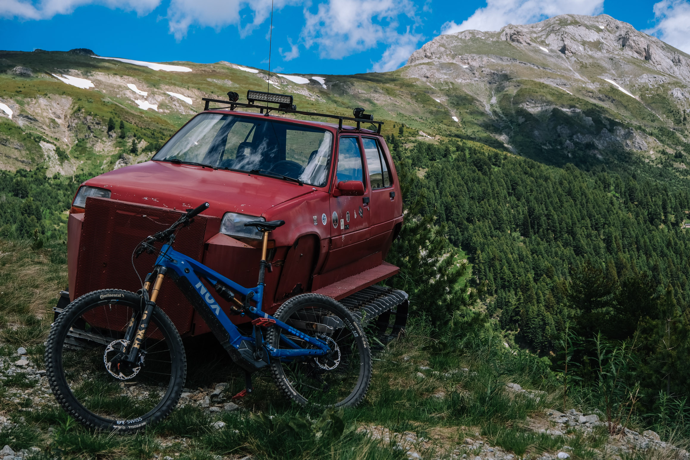 An e-bike leaning against an abandoned red truck on the high pastures of Bjeshka e Belegut